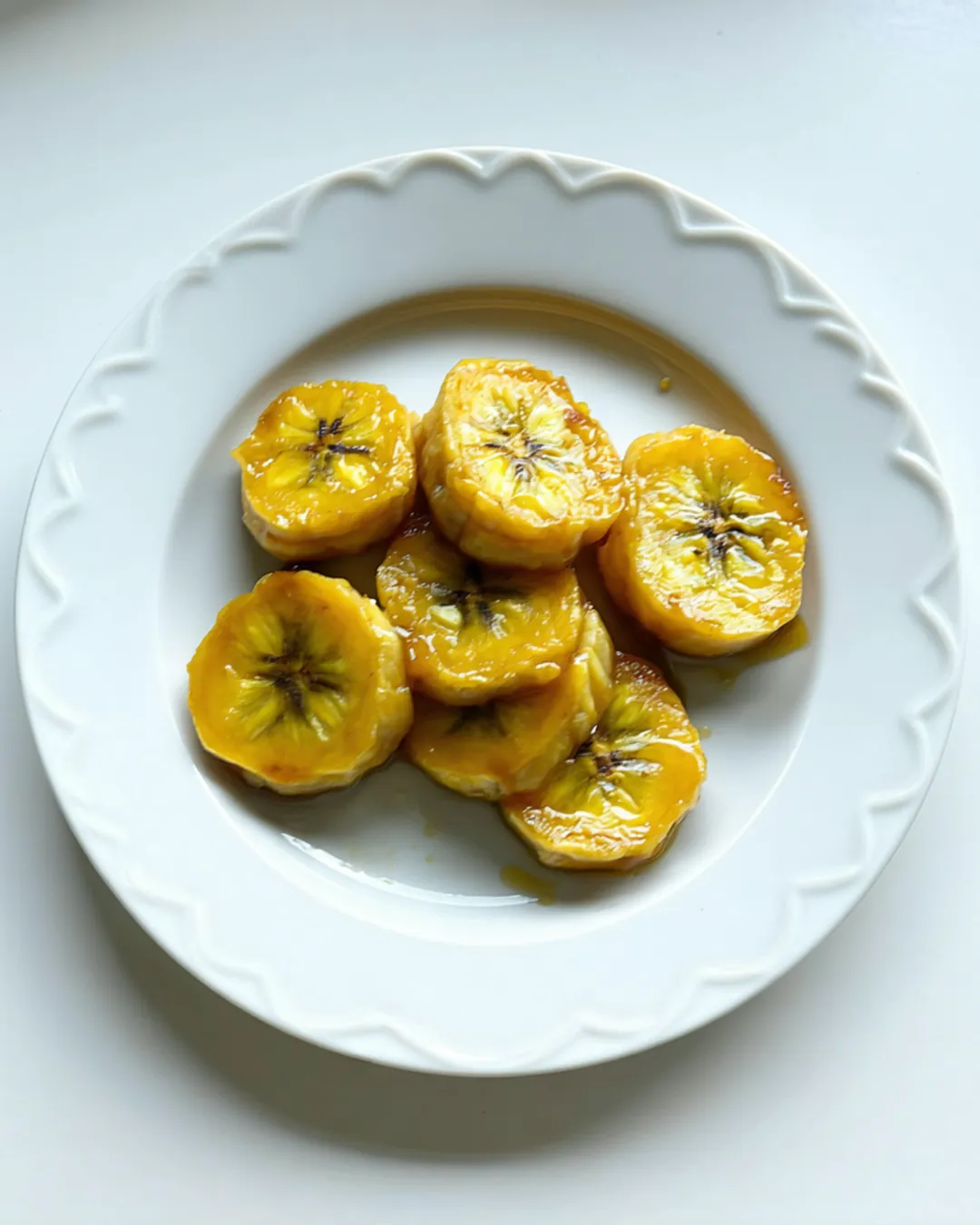 Soft caramelized sweet plantain rounds on a white plate